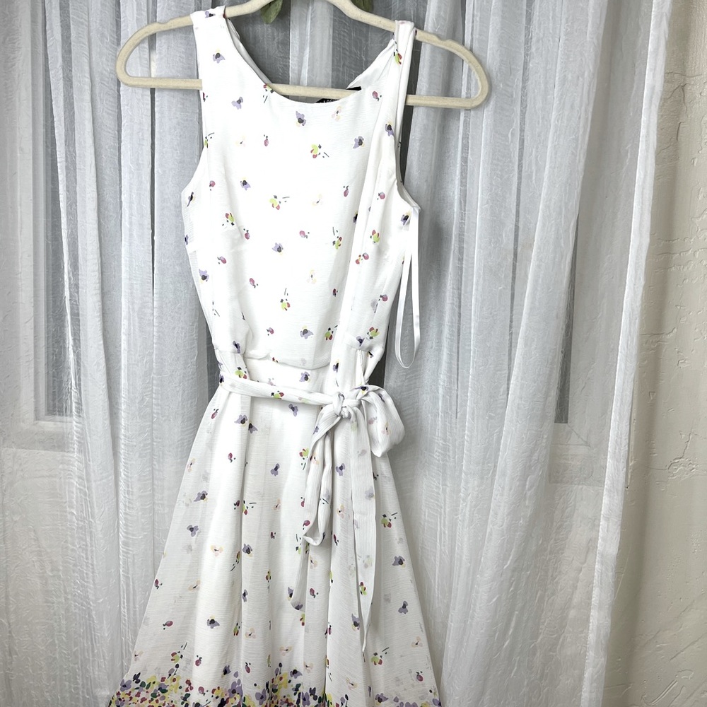 White flowy sundress with yellow, blue, purple, pink bouquet designs.